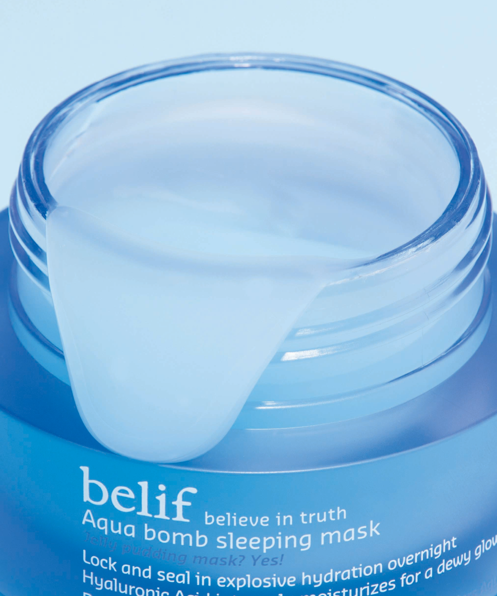 A jar of belif Aqua Bomb Sleeping Mask is open, with some of contents spilling over the side of the jar