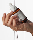 A hand holding Alltimate Vegan Mucin Peptide 8 Serum with jelly serum texture dripping down from the bottle.
