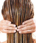 A closeup of a model facing backwards, holding her silky lathered hair.