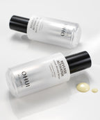 Two bottles of Reverse Activator Retinol Wrinkle Serum laying opposite directions on a white surface, next to a quarter-sized drop of product.
