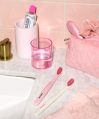 A photo of a bathroom sink counter, showing the white and pink Euthymol Whitening Toothbrushes.