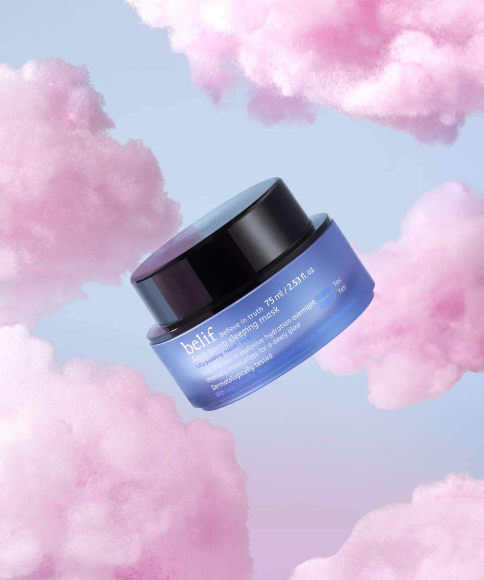 A jar of belif Aqua Bomb Sleeping Mask floats in front of a background of fluffy pink clouds